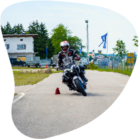Motorradfahrer fährt um Pylonen auf dem Übungsplatz